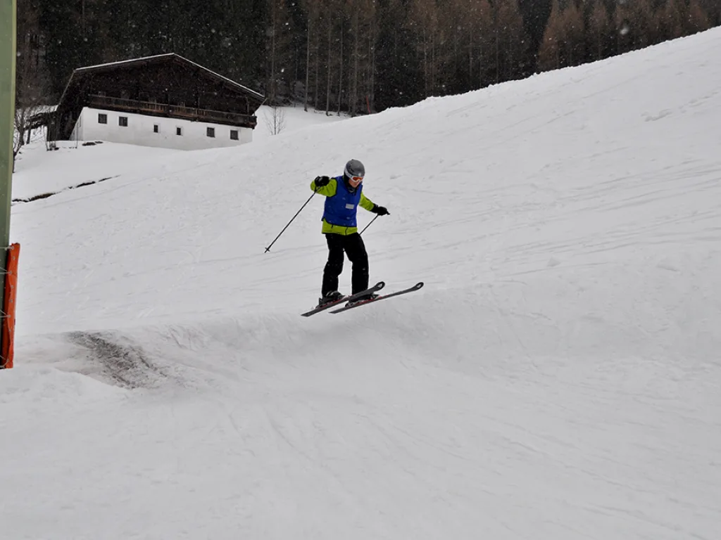 Skifahrer in gelber Jacke fährt den Hang hinunter.